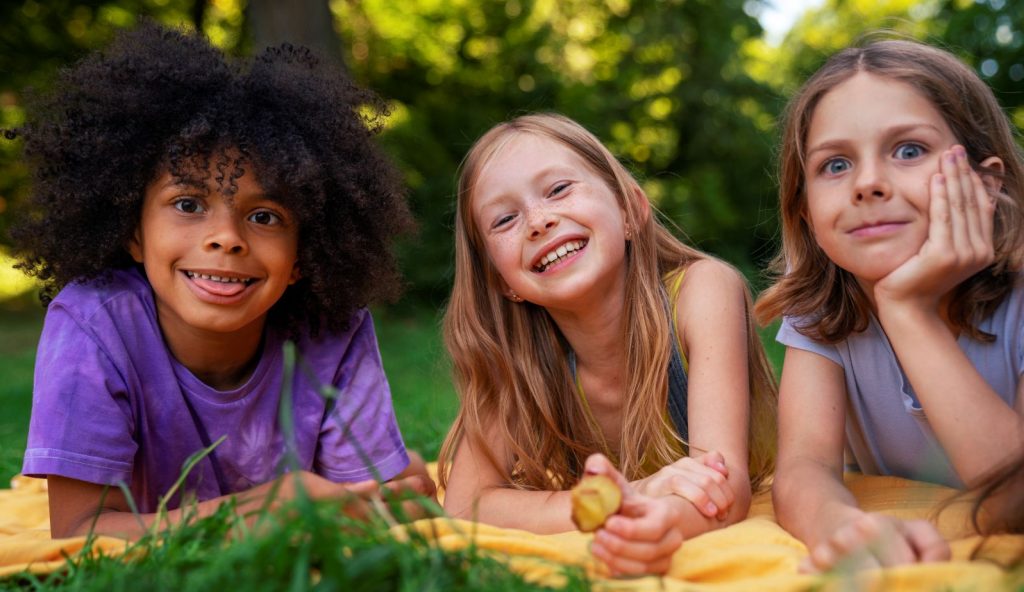 Groupe d'enfants souriants jouant ensemble en plein air, illustrant la joie du jeu libre.