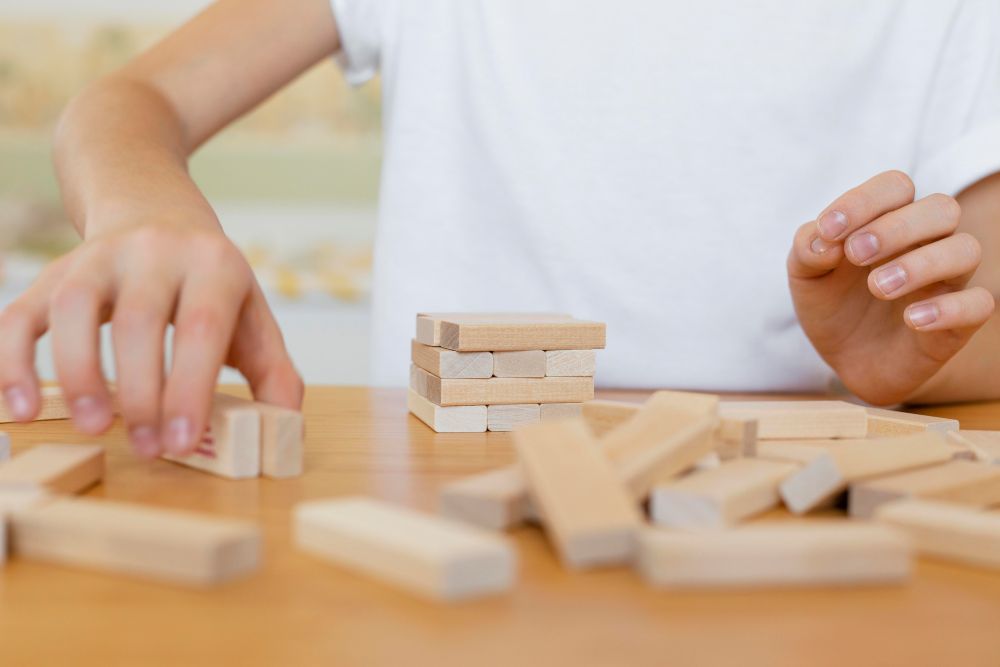 Deux enfants concentrés qui collaborent pour résoudre un casse-tête en bois.